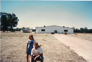 Andrew with daughter Amy stand in front of a bare paddock with the plain white shed that would become Warrabilla. Circa 1996
